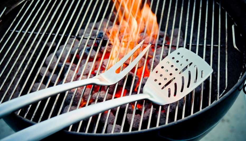 Barbeque Tongs Sit On Grill With Flame In Background, AARP Home And Family, Home Improvement, How To Get The Best Grille
