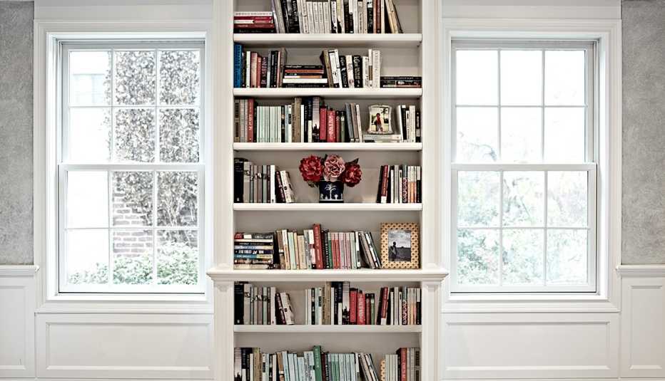 Una estantería llena de libros ubicada entre dos ventanas.