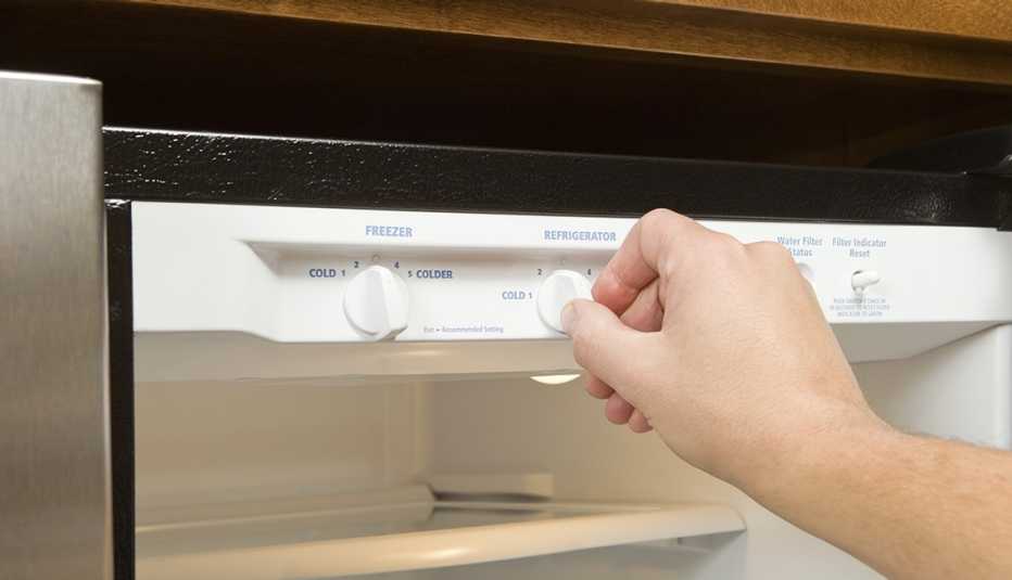 Primer plano de una persona ajustando la temperatura de un refrigerador
