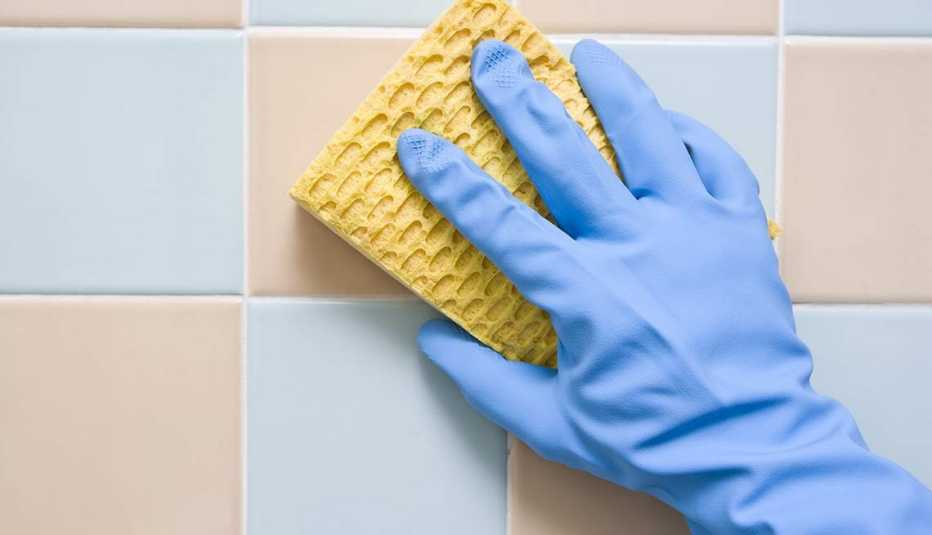Claves para que tu baño luzca siempre limpio - Mano fregando la pared de la ducha
