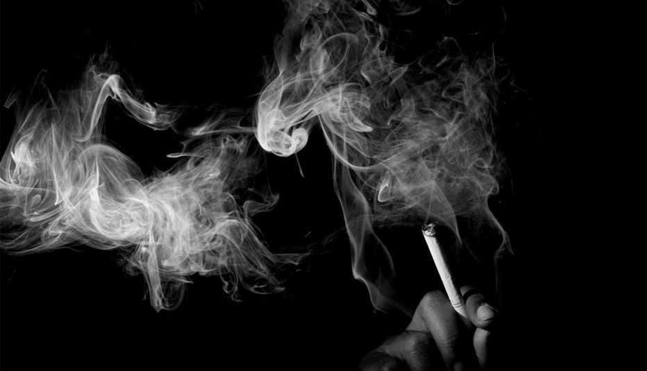 Una mano sosteniendo un cigarrillo rodeado de humo