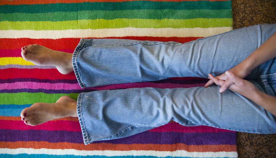 Una persona con las piernas sobre una alfombra multicolor