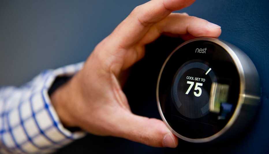 Persona ajustando un termostato NEST, temperatura actual setenta y cinco