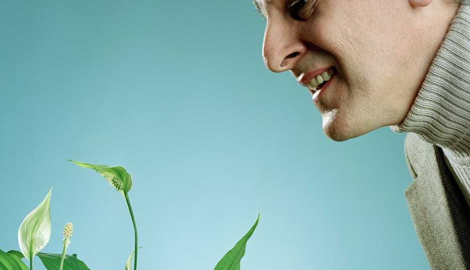 Hombre sonriente viendo una planta