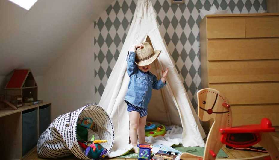 Niño con sombrero de vaquero jugando en una choza de juguete