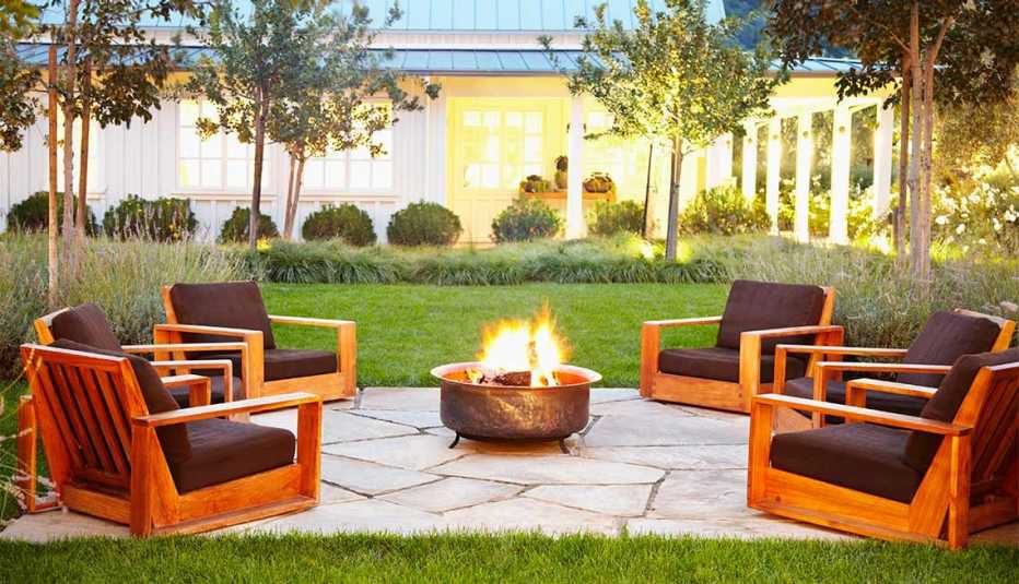 Cinco sillas de madera alrededor de un pozo de fuego en un patio