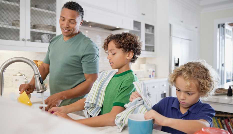 Lo que pueden hacer papás e hijos para sorprender a mamá - Papá y sus dos hijos lavan los platos en la cocina