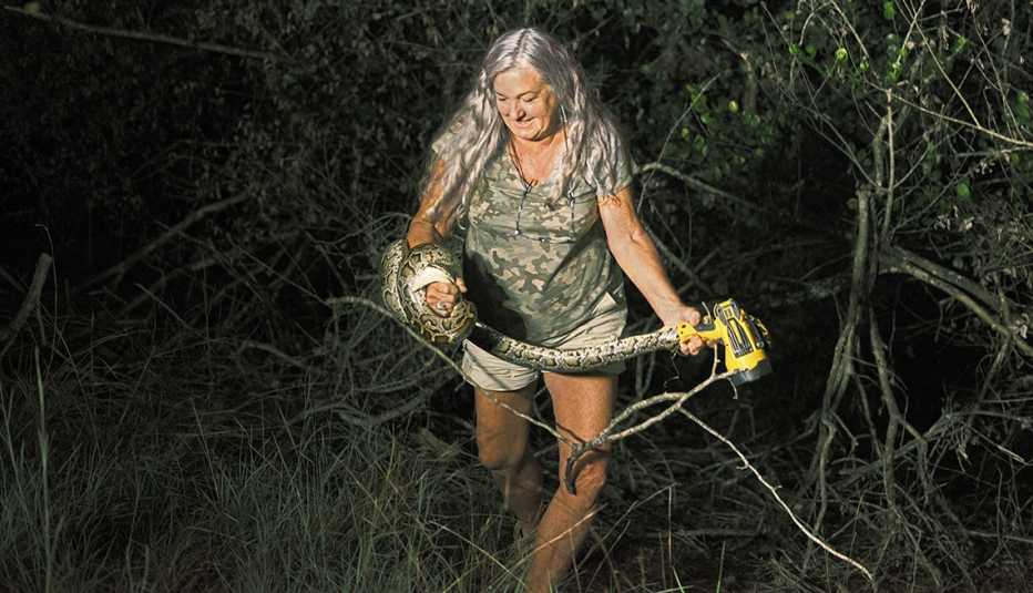 Anne Gorden-Vega, de 64 años, madre de dos hijos adultos, es artista de cerámica en Miami y contratista de la Comisión de Conservación de Vida Silvestre y Pesca de Florida. En la imagen, atrapando una pitón en el bosque por la noche.