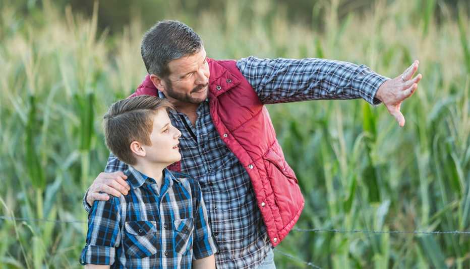 Un agricultor con su hijo, de 13 años de edad, de pie en un campo de cultivos.