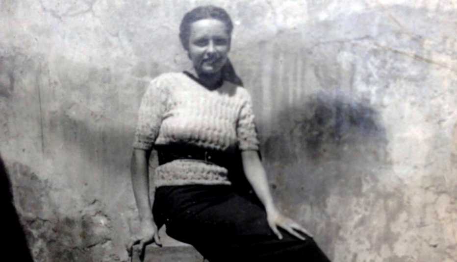 Foto antigua de una mujer que sonríe mientras está sentada.