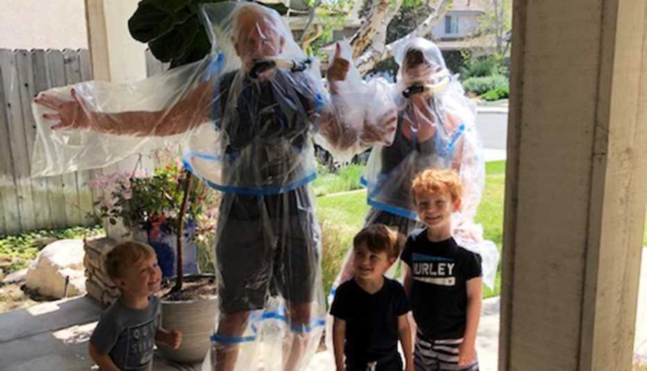 Abuelos en traje de plástico posan para una foto con sus nietos