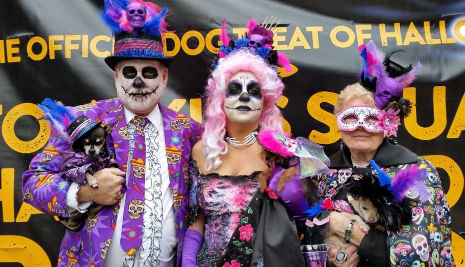 Un grupo de personas con sus mascotas disfrazadas para Halloween con disfraces relacionados al Día de los Muertos