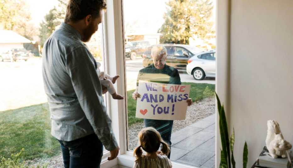 Abuelo muestra un letrero a su familia a través de la ventana