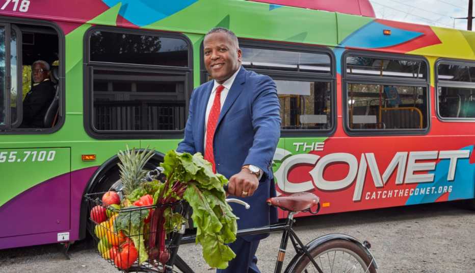 El alcalde de Columbia, Steve Benjamin, posa con una bicicleta frente a un autobús