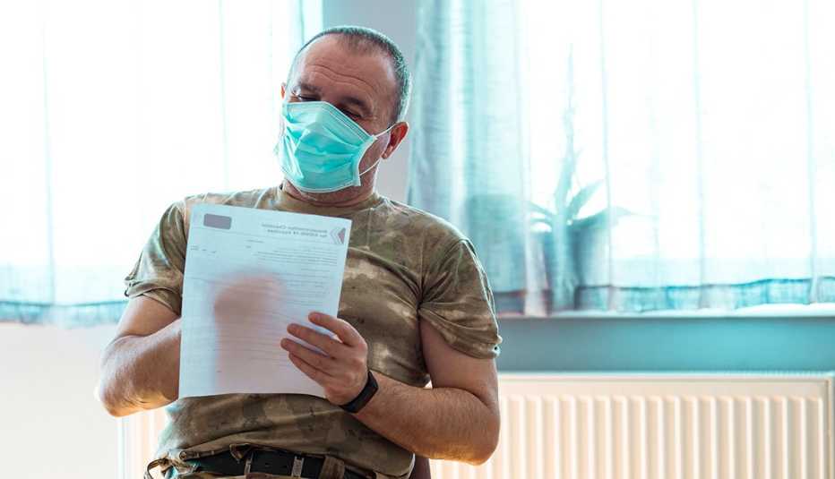 Un veterano militar con una máscara quirúrgica llena un formulario de vacunación contra la COVID-19