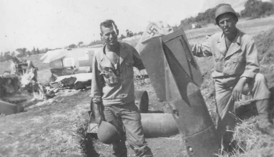 Soldados posan con una bomba frente a un avión alemán destrozado