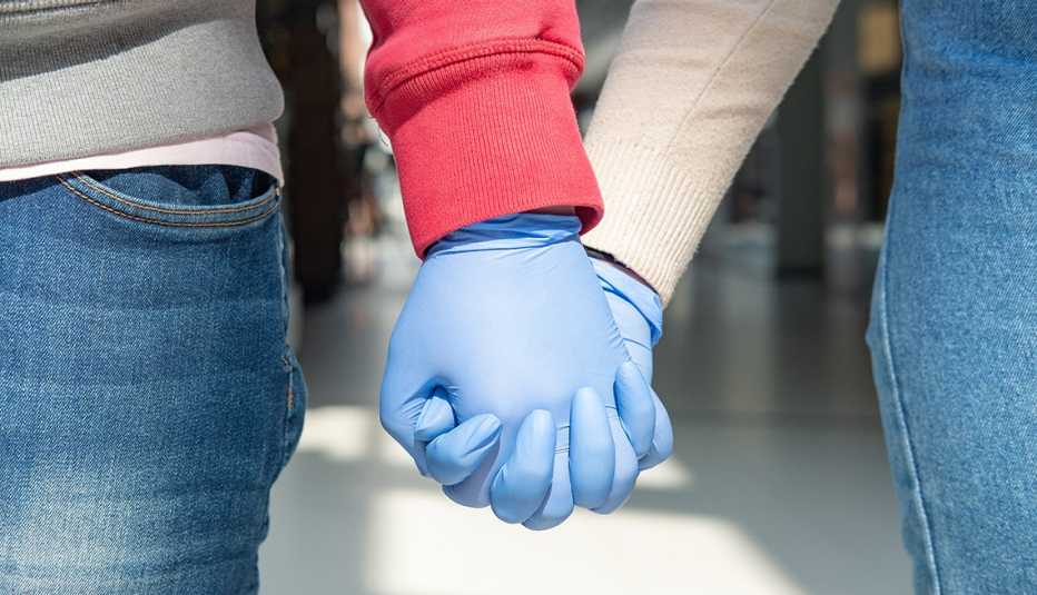 Dos personas tomadas de la mano con guantes