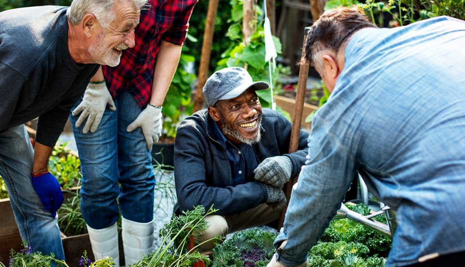 Grupo de personas sonríen mientras plantan vegetales