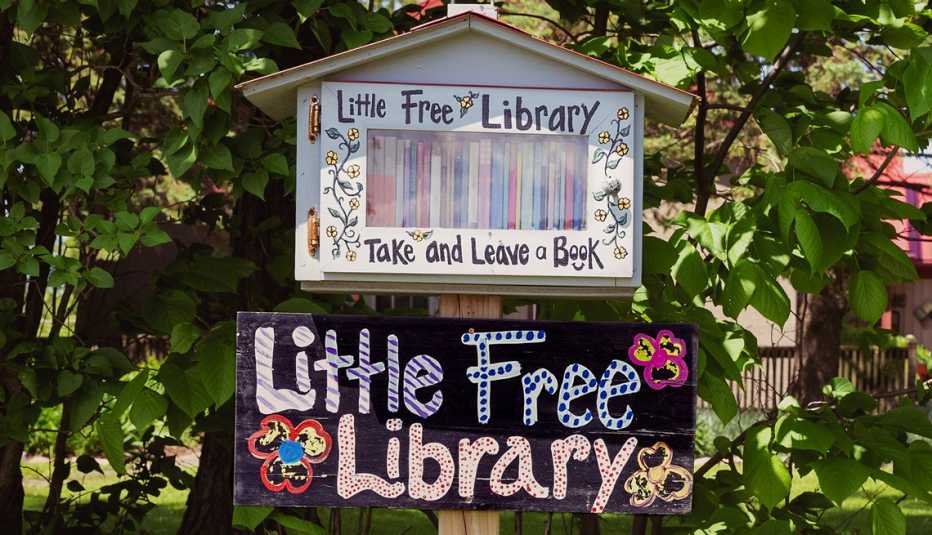Una casita pequeña llena de libros y letrero que dice Biblioteca gratis