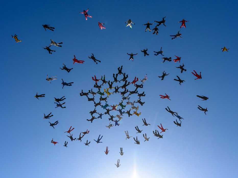 Grupo de más de cincuenta paracaidistas hacen una formación en el aire mientras caen al vacío