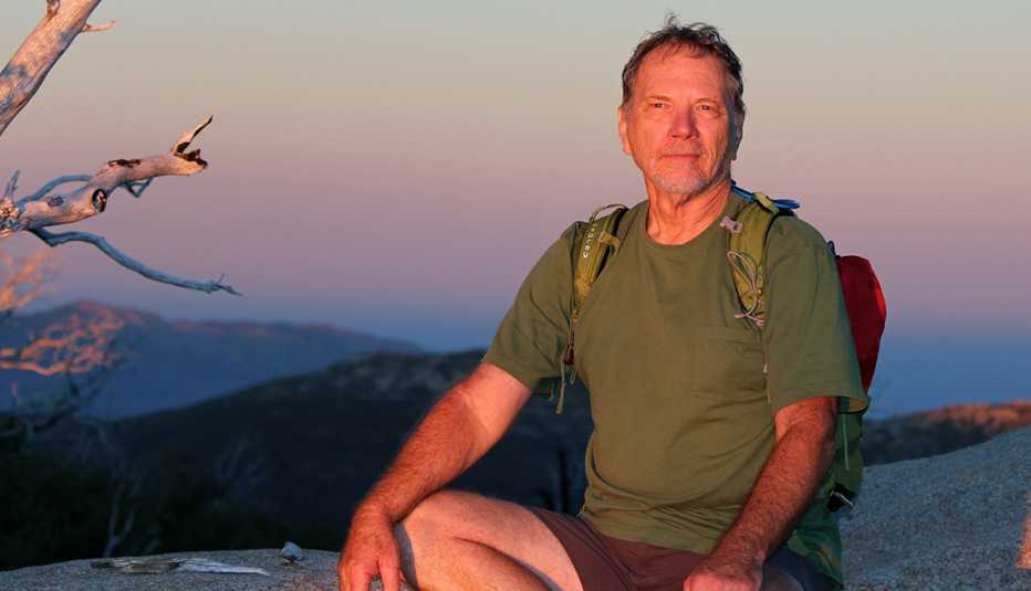 John Starr con una mochila en una caminata en la cima de una montaña