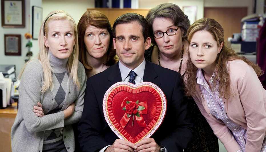 Steve Carell sosteniendo un corazón de San Valentín mientras está rodeado por los miembros del elenco femenino de The Office.