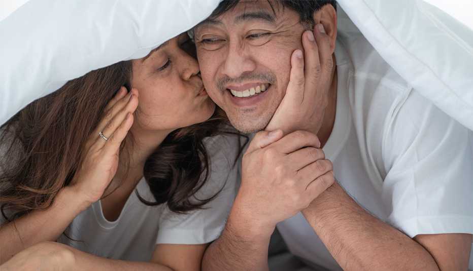 Hombre sonriente disfruta de un beso de su cónyuge