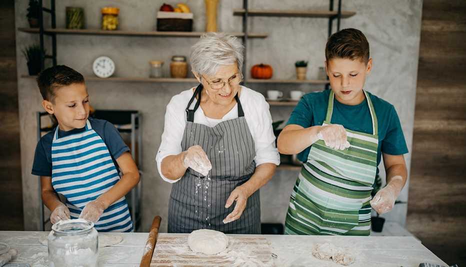 La abuela y sus dos nietos trabajan con harina para hacer galletas