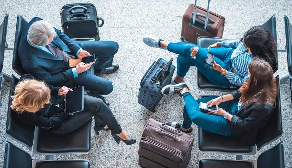 Viajeros en el aeropuerto manipulan sus dispositivos inteligentes