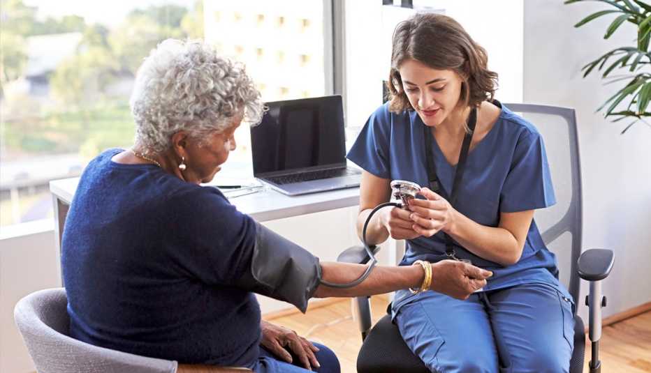 Una enfermera le muestra al paciente cómo tomar y leer su presión arterial