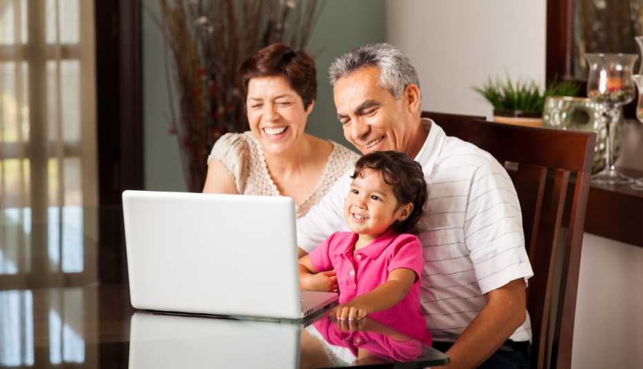 Abuelos sonríen con su nieta mientras ven la pantalla de una computadora