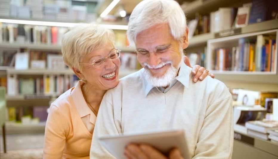 Un hombre y una mujer leen en la biblioteca con la ayuda de una tableta digital