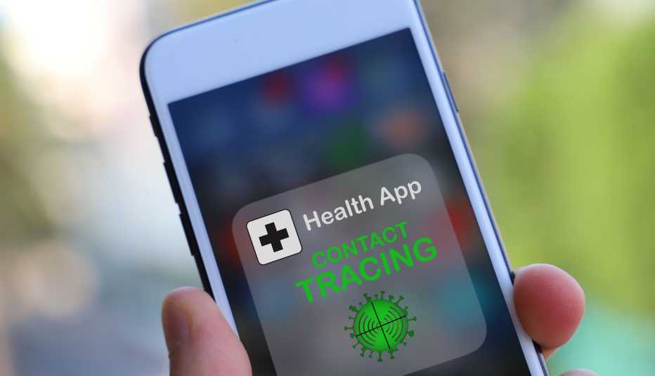 Mano sostiene un teléfono inteligente con una aplicación de salud que rastrea a los individuos que la tengan en su teléfono