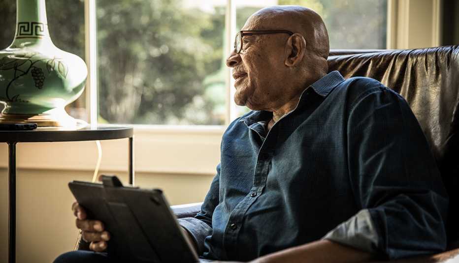 Un hombre mayor usa una tableta electrónica en su casa