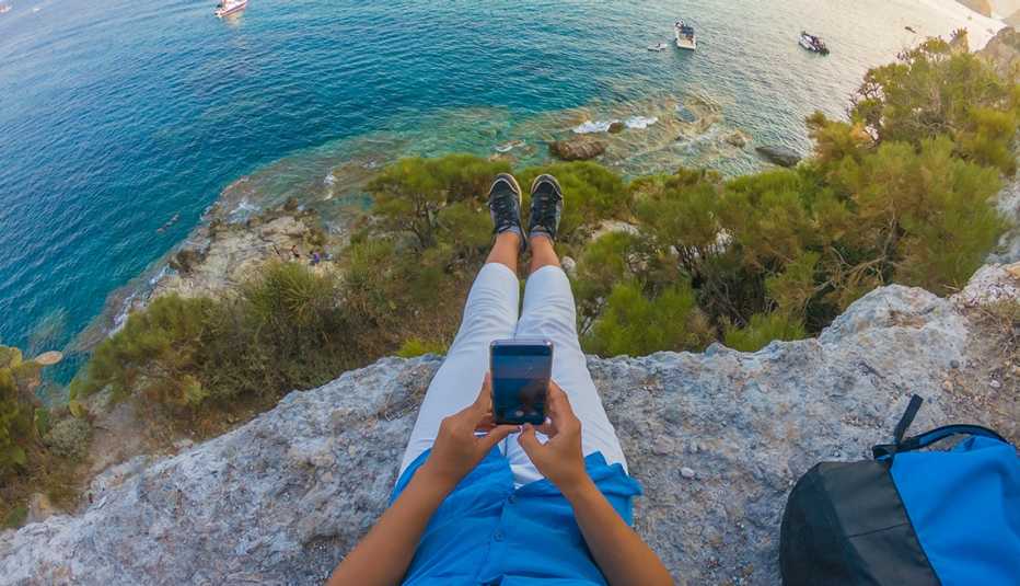 Mujer toma una foto del mar desde una colina