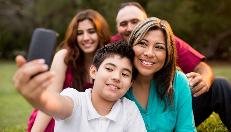 Un hijo adolescente, junto a su familia, toma una foto selfie con un teléfono móvil
