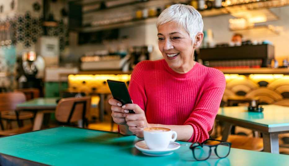 Mujer sentada en un restaurante mientras revisa su teléfono