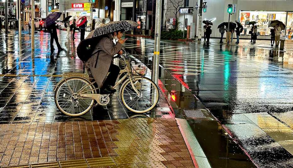Mujer en bicicleta se cubre con una sombrilla bajo la lluvia