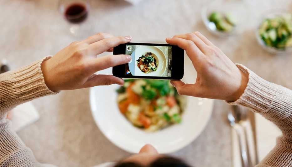 Mujer usa un teléfono inteligente para tomar una foto de su comida