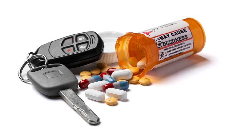 Llaves de automóvil junto a una botella de medicamentos y pastillas de colores.