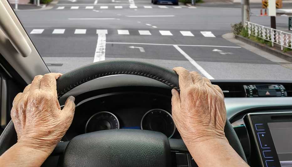 Manos de una persona mayor sobre el volante de un automóvil