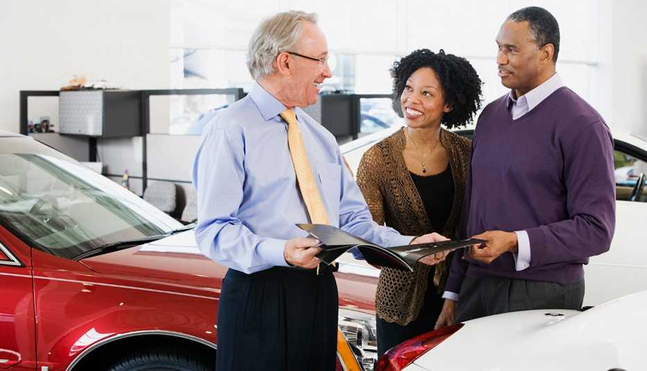 Una pareja que busca comprar un automóvil habla con un vendedor