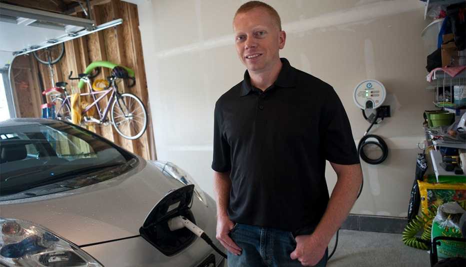 Tim Edmonson posa para una foto junto a la estación de carga de su auto eléctrico