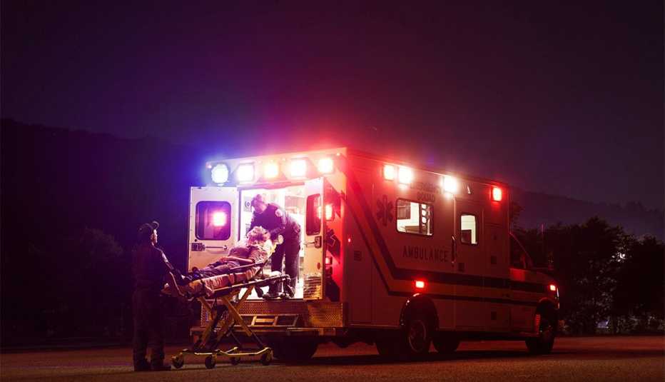 Trabajadores de servicios médicos de emergencia suben un paciente a una ambulancia