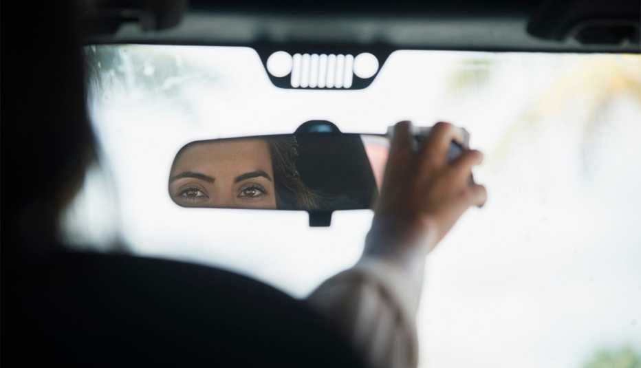 Mujer ajustando el espejo retrovisor de su auto