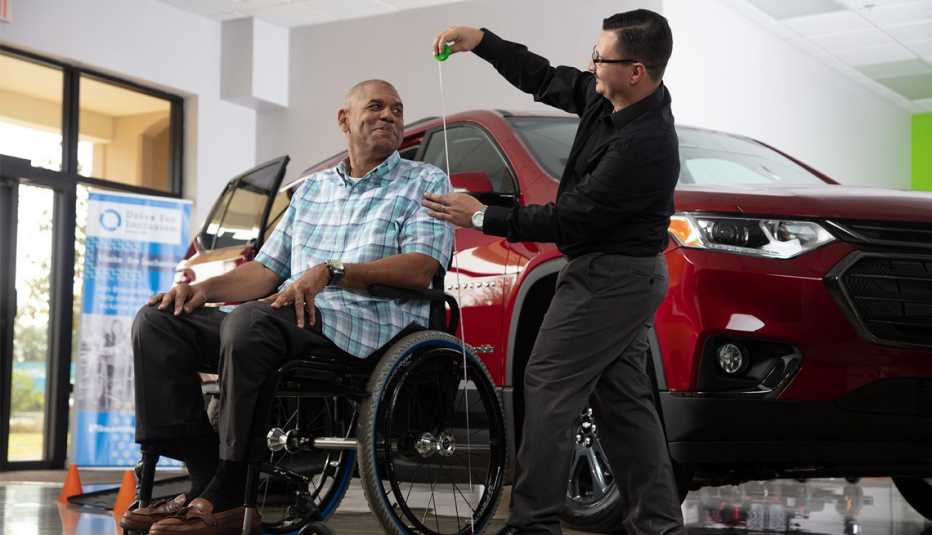 Un hombre mide la altura de un adulto mayor sentado en una silla de ruedas