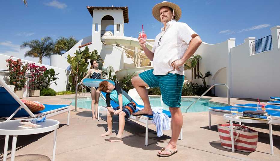 Un hombre con dos niños y una piscina al fondo disfrutando de unas vacaciones, porque ha ahorrado para la jubilación.