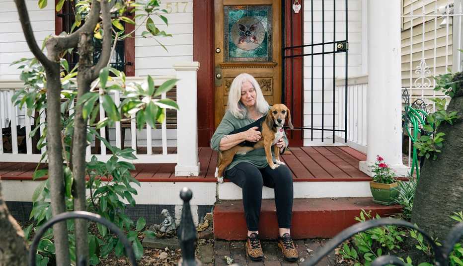 Susan Kelly sentada en el porche de su casa con su beagle Tyson en el regazo