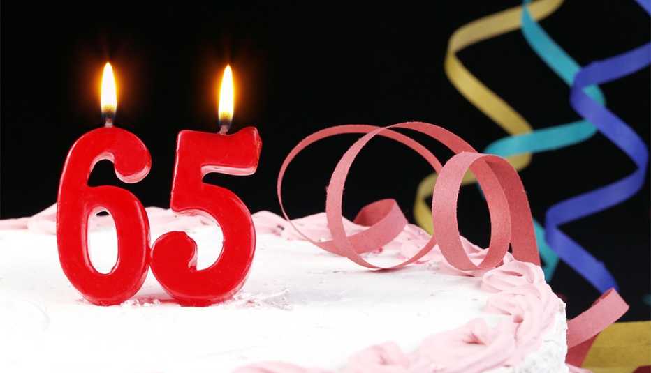 Pastel de cumpleaños con velas en forma de número 65.