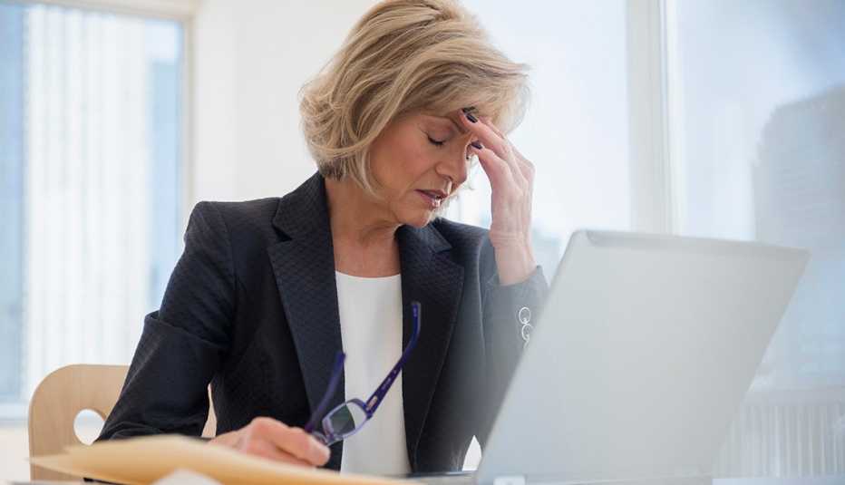 Mujer con dolor de cabeza sentada frente a su computadora.